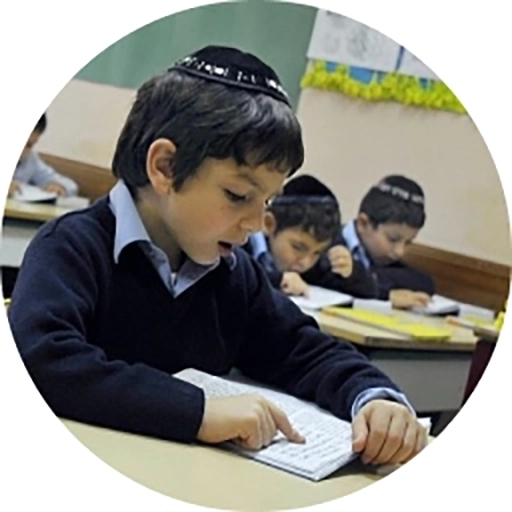 Image of a boy wearing a yarmulke, reading a book.
