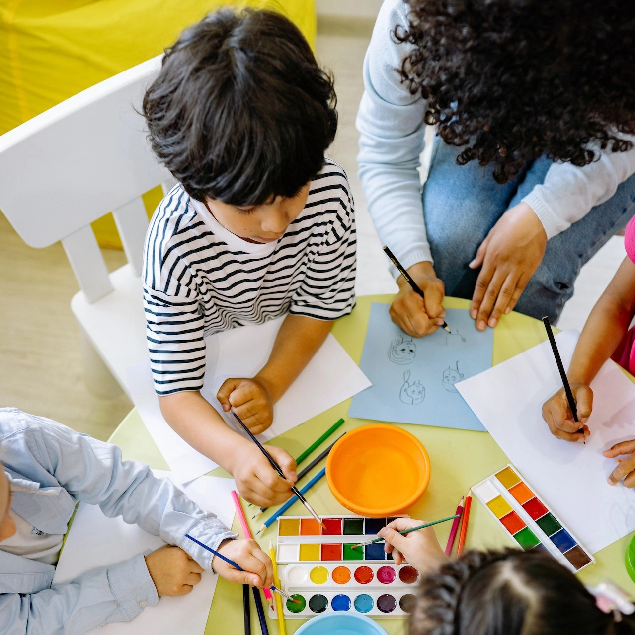 Image of a group of young children drawing and painting with watercolors.