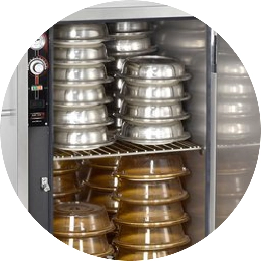 Image of food covered with silver lids in a warming cabinet.