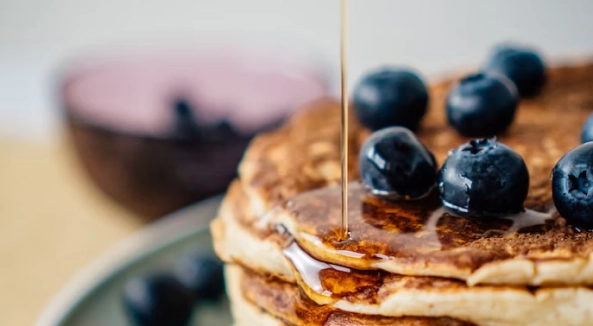 Image of pancakes topped with blueberries and syrup.