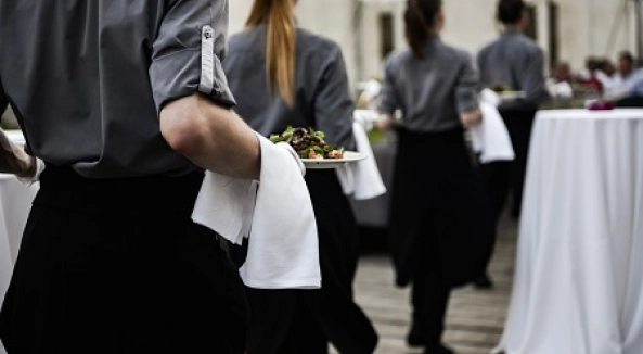 Image of servers serving food at a catering event.